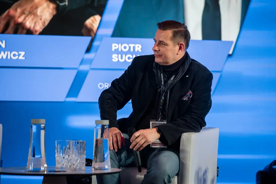 Panelista słucha dyskusji z uśmiechem na scenie EXS 2024