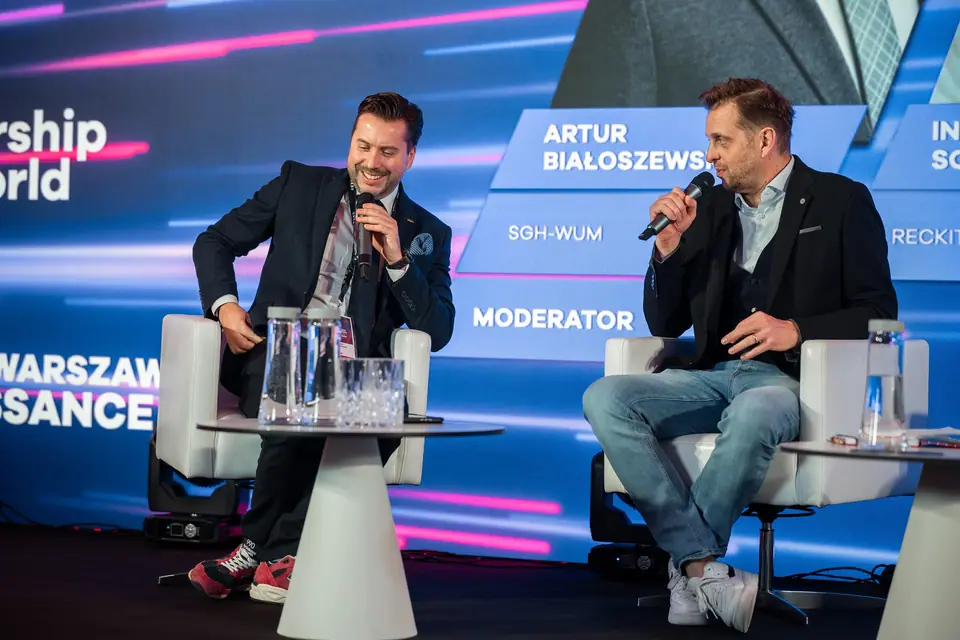 Uśmiechnięty panelista przy mikrofonie w rozmowie na scenie EXS 2024